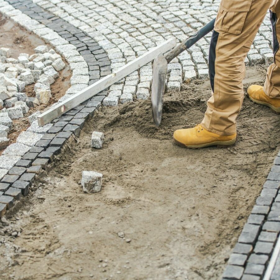 Worker Paving Residential Path Using Granite Bricks